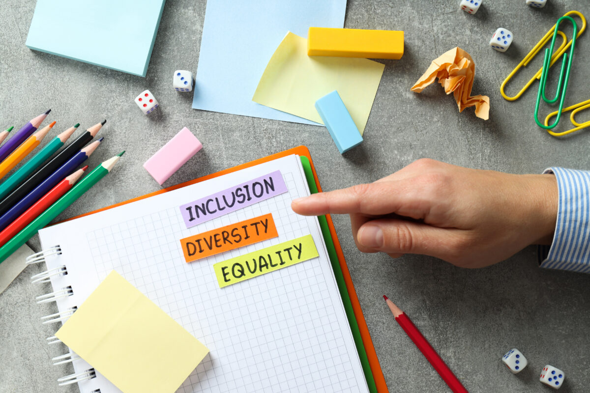 desk with office supplies and notebook with the words inclusion, diversity and equality