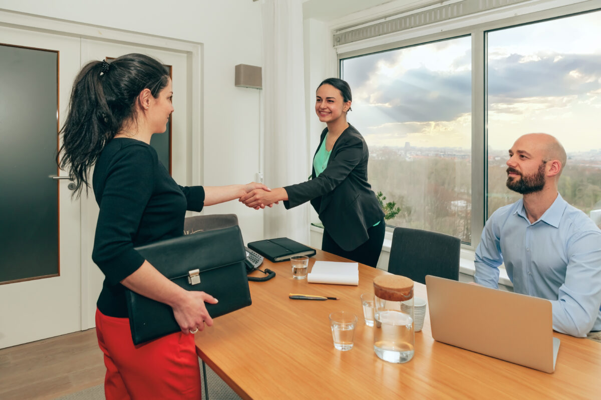 handshaking at work interview - female colleagues greet each other in the office